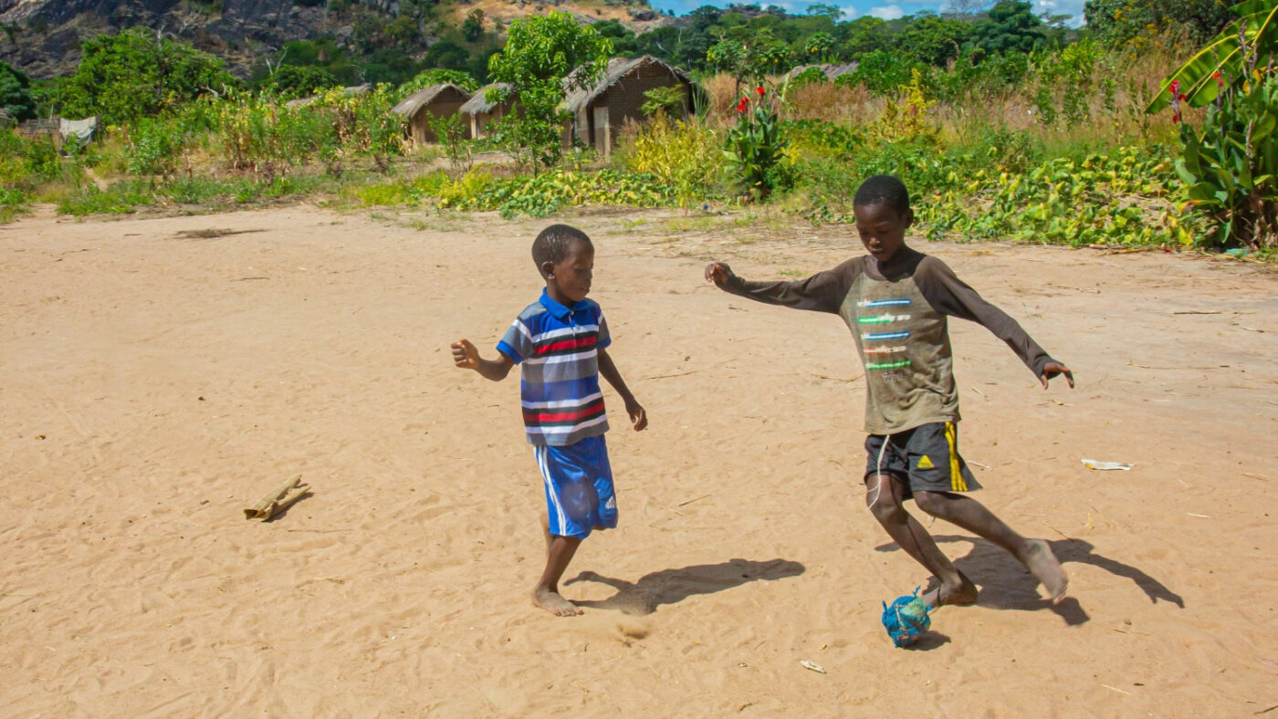 Mohamed plays football outside with a friend.