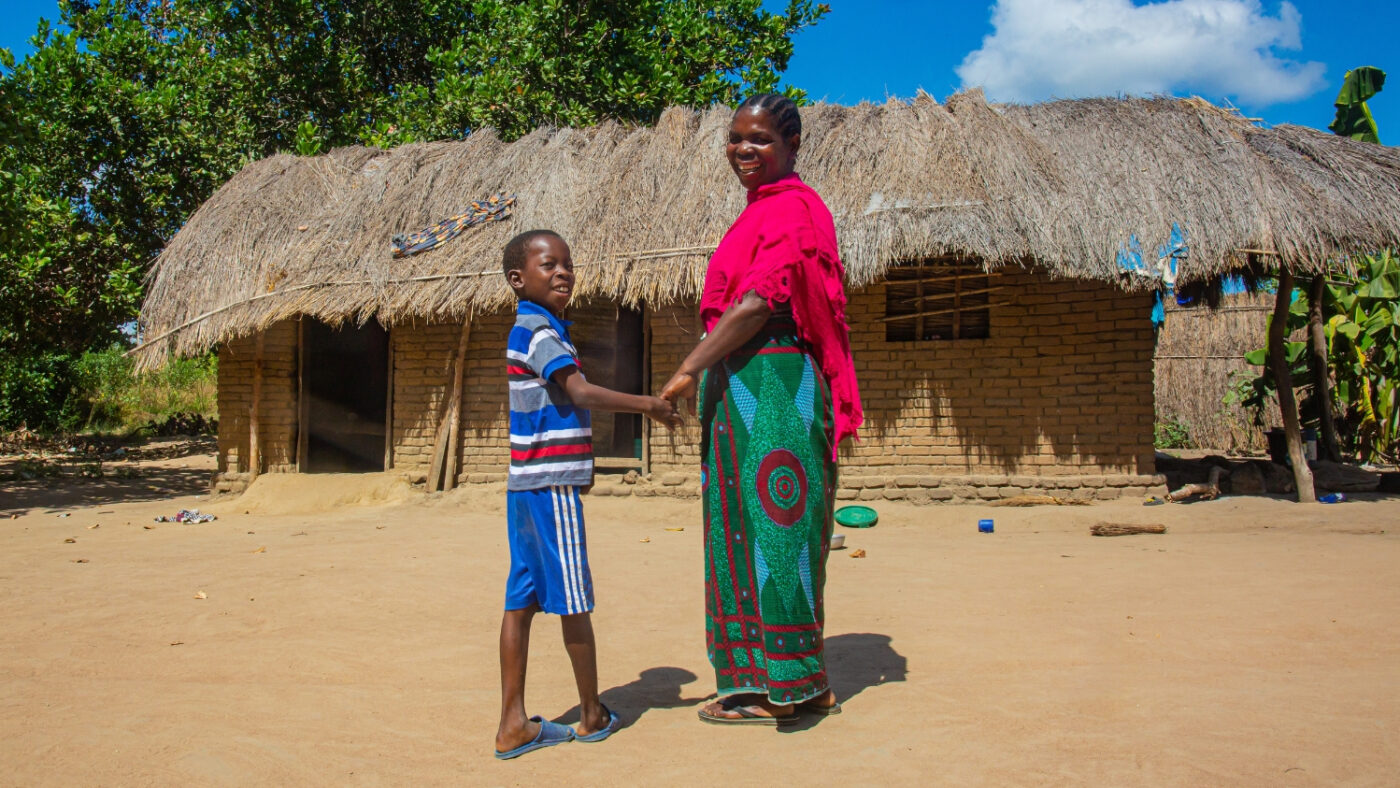 Mohamed and Sophia walk outside their home in Tanzania.