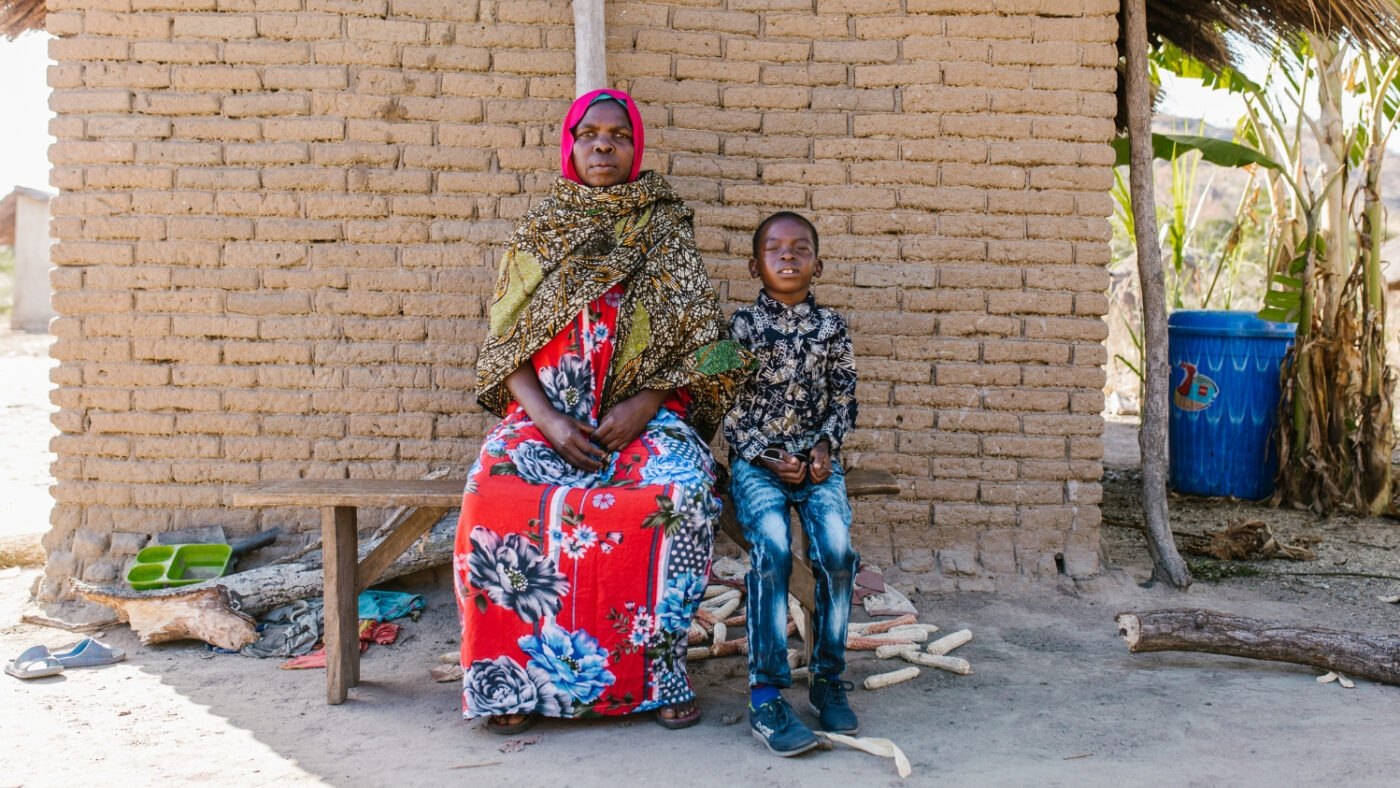 Mohamed sits outside his home in Tanzania with his grandmother, Sophia.