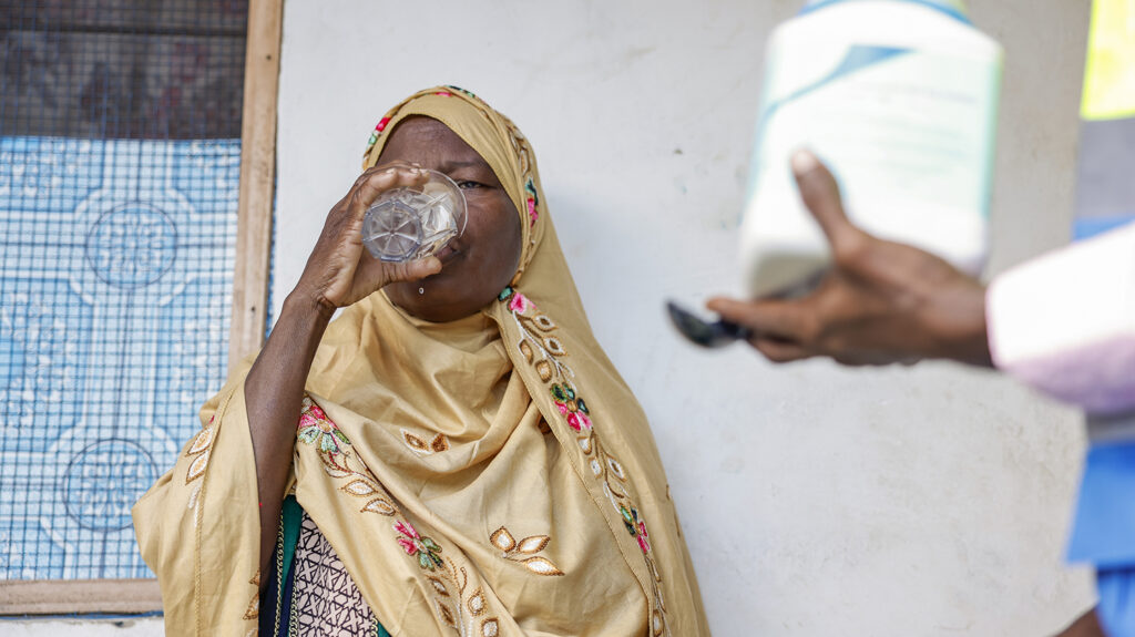Mzowele drinks water after taking medication for lymphatic filariasis.