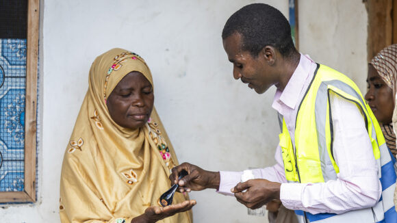 Community drug distributor Seif gives Mzowele albendazole to treat lymphatic filariasis.