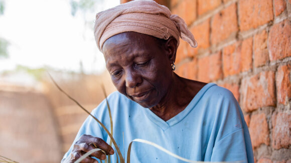 Achiwa weaving outside her home in Malawi after her successful trachoma operation.
