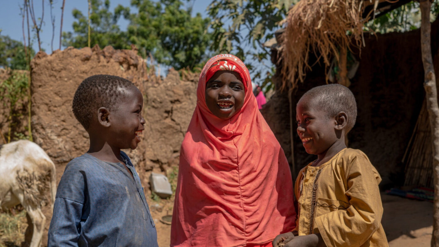 Aisha stands outside smiling with her cousins.