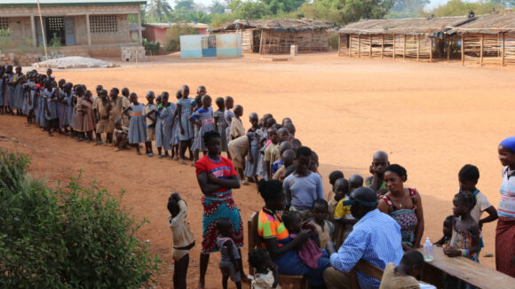 A long line of people queue for eye health screening in a remote area of Cote d’Ivoire.