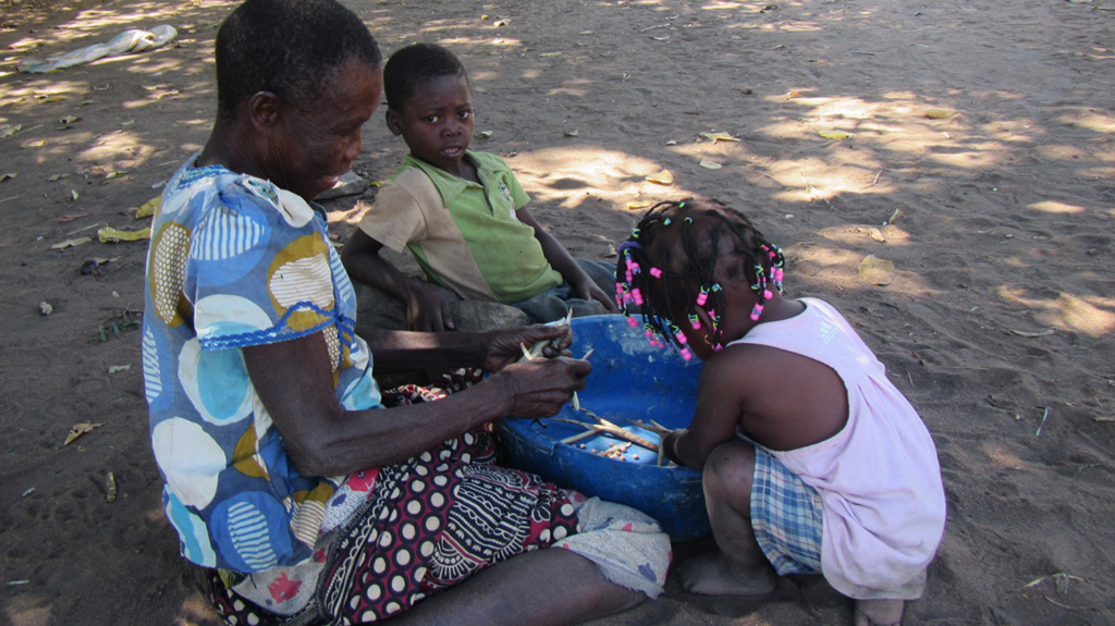 Caliha prepares food outside with two children.