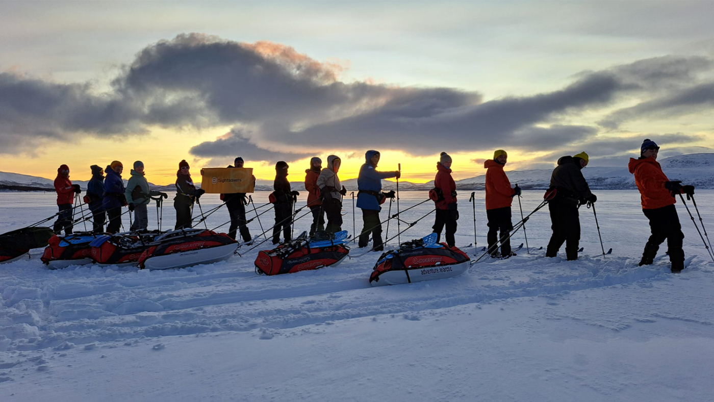 Participants on the First Light for Sight Arctic expedition watch the sunrise while wearing skis.