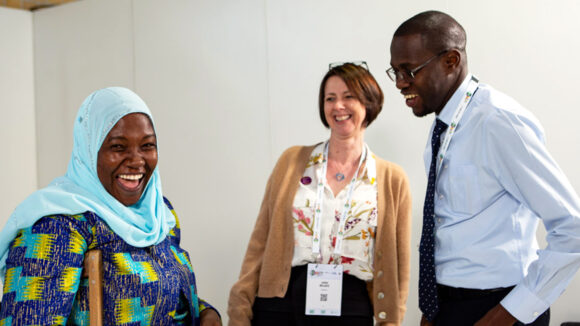 Three smartly dressed people laugh at the conference.