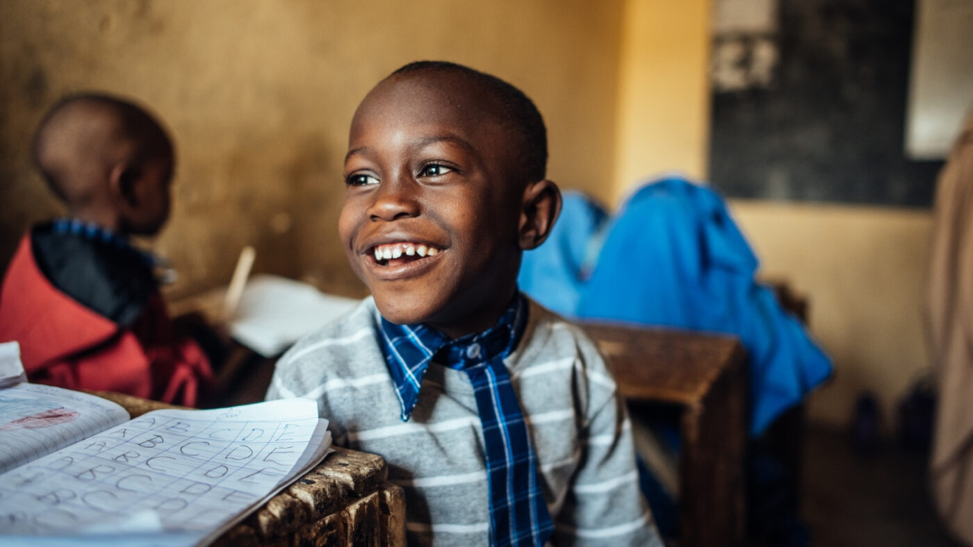 Muhammad looks back and smiles while sitting in class.
