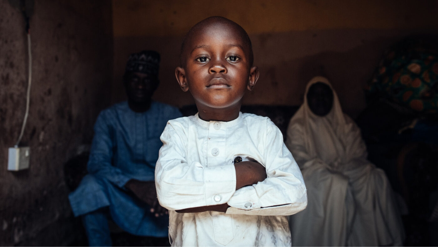 Muhammad stands inside his home with his arms folded.