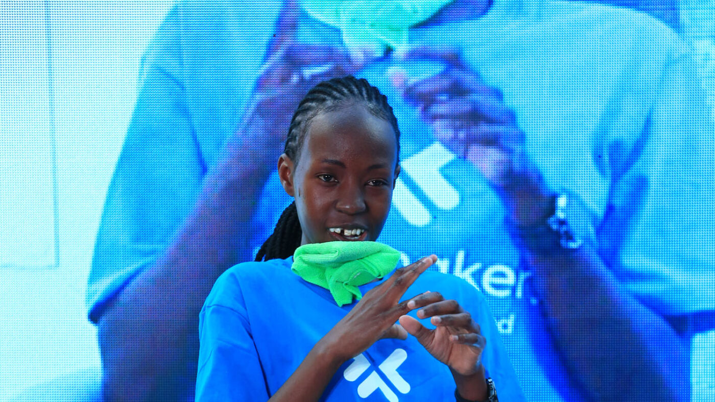 Maryanne sits on stage with a large TV screen behind her. She's wearing a Futuremakers T-shirt.