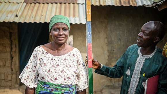 A woman is measured using a dole pole by a male volunteer.