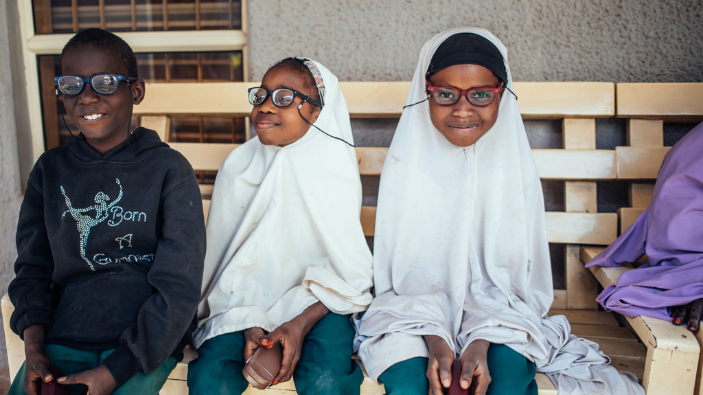 Three children smiling with glasses on.