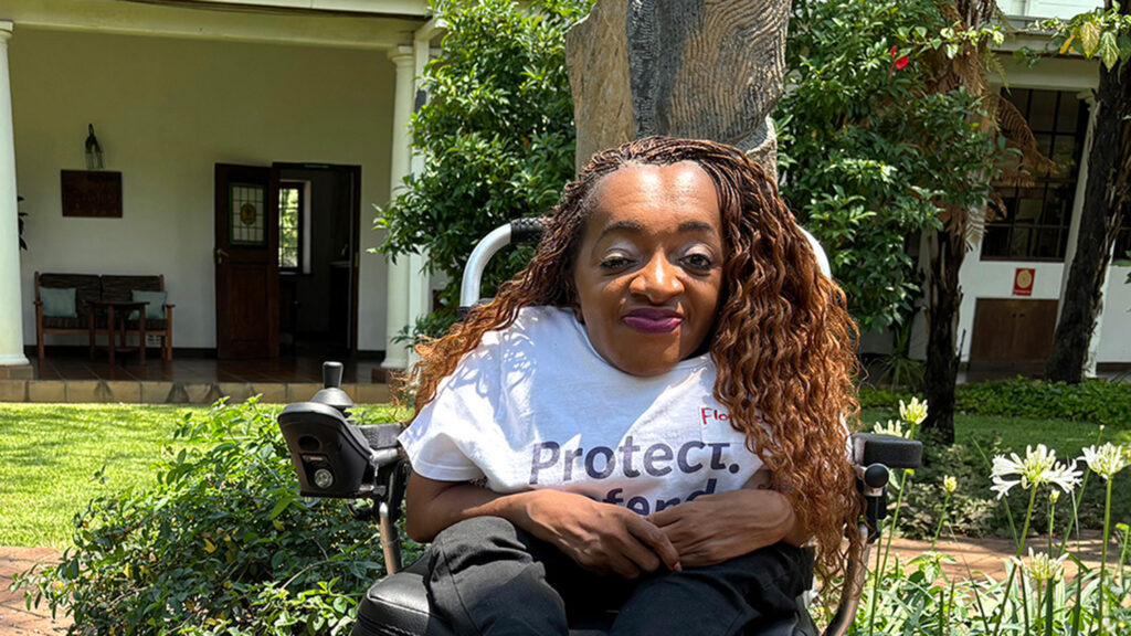 A woman with a physical disability sits in a motorised wheelchair.