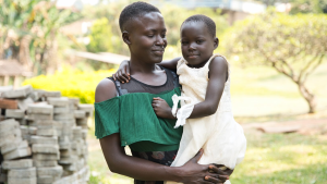 A little girl smiles while being carried by a woman.