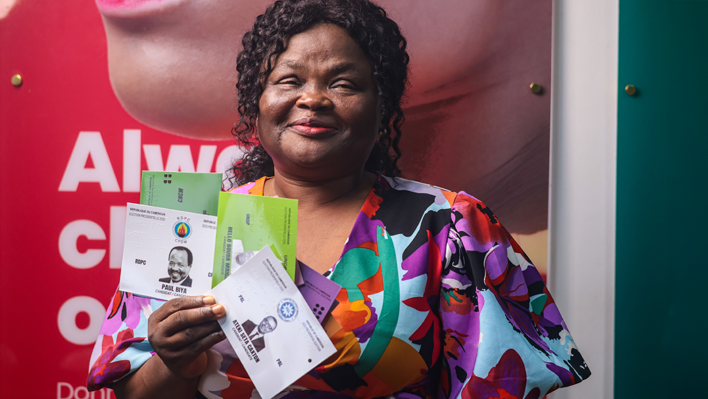 A woman smiles, holding up tactile voting cards.