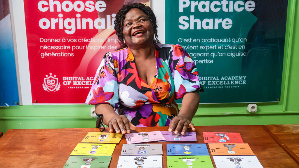 A woman smiles as she sits behind a desk with colourful cards.