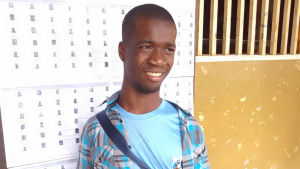 A young man smiles and looks into the distance.