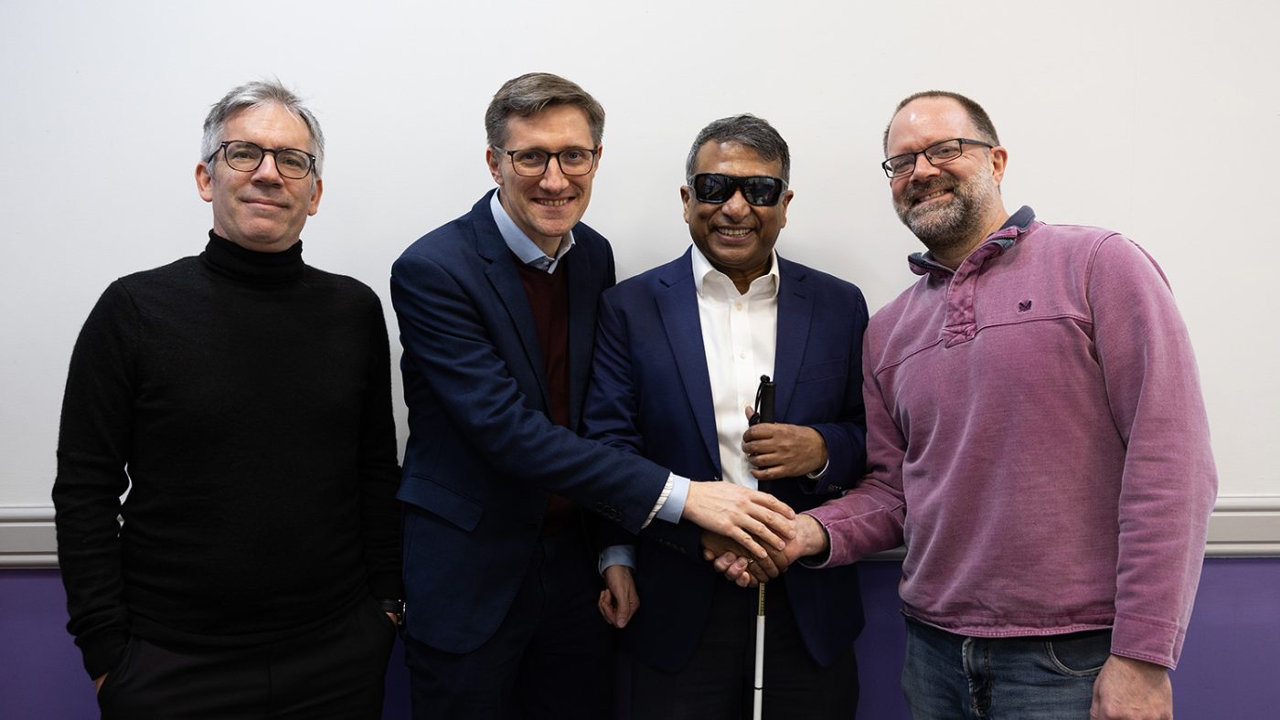 Four men wearing office attire shake hands.