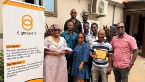 The Sightsavers Sierra Leone country team pose for a group photo next to a Sightsavers banner.