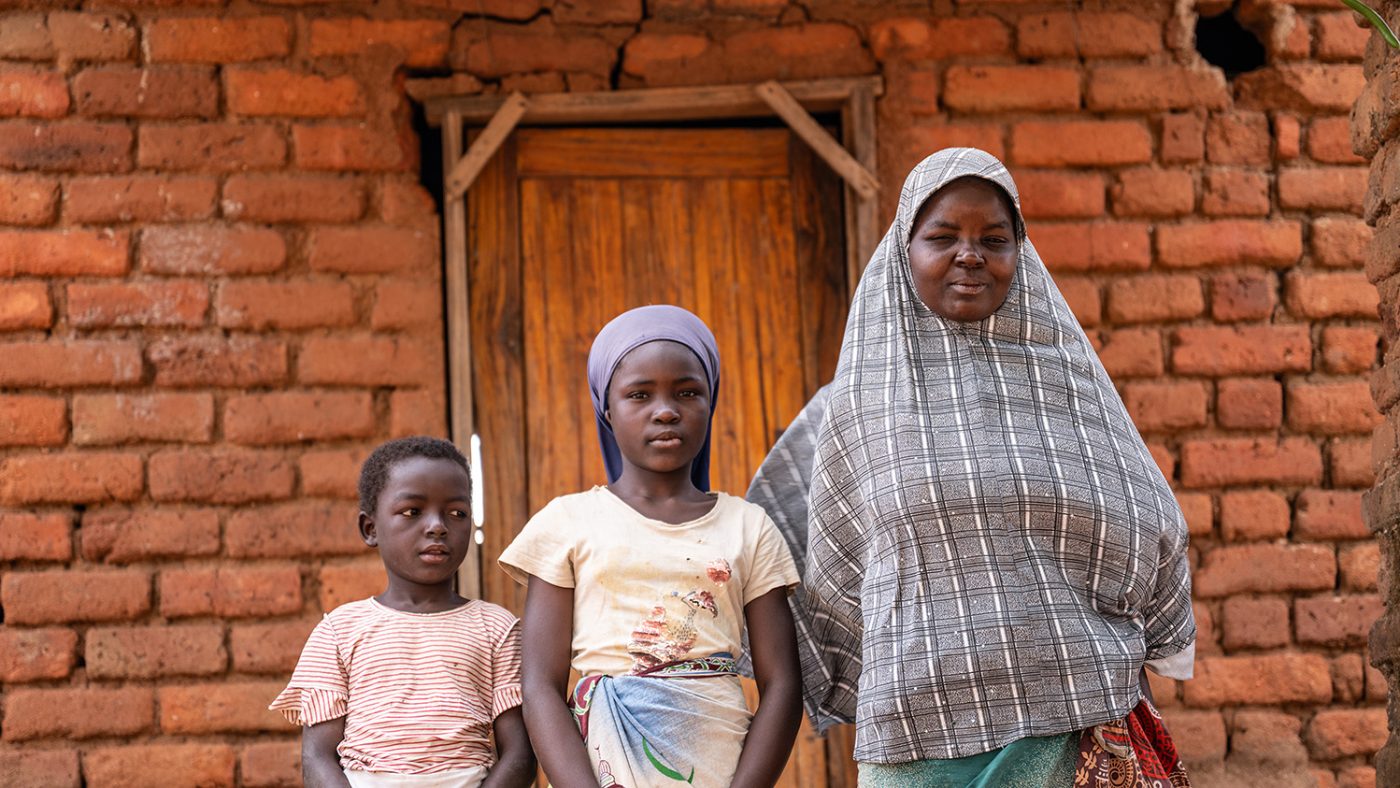 Ruth stands outside a brick house with two of her children.