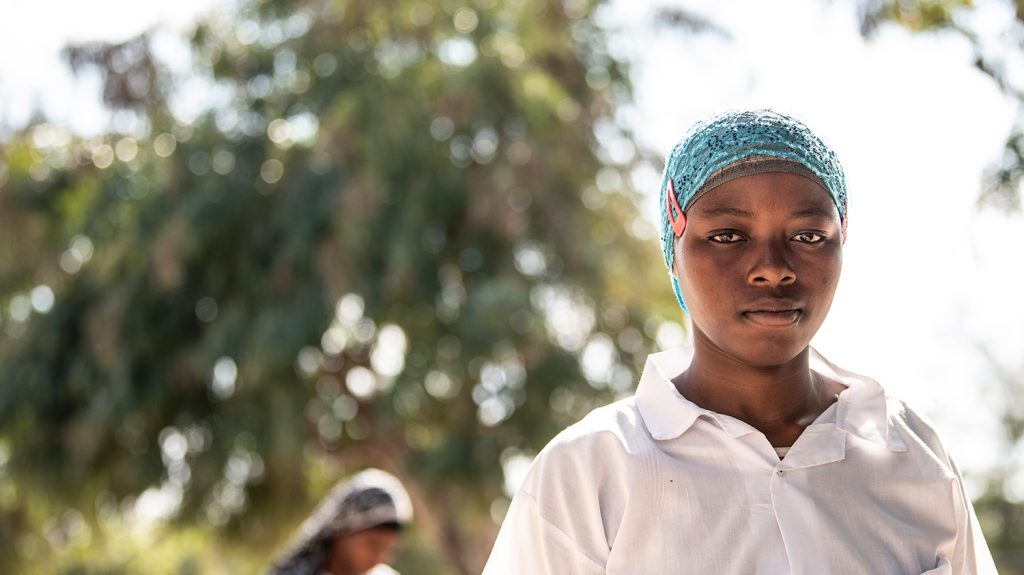 Cidalia is wearing a white shirt and a headscarf.