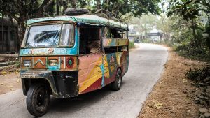 A tuk-tuk travels down a road in Bangladesh.